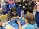 ARRL Education and Learning Support Specialist Max Freedman, N4ML, watches as a young ham works on a soldering project at the youth booth.